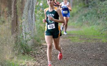SHAPE's Zuzanna Hebda runs along a fence during a Sept. 30, 2023, meet at Ramstein High School on Ramstein Air Base, Geramny.