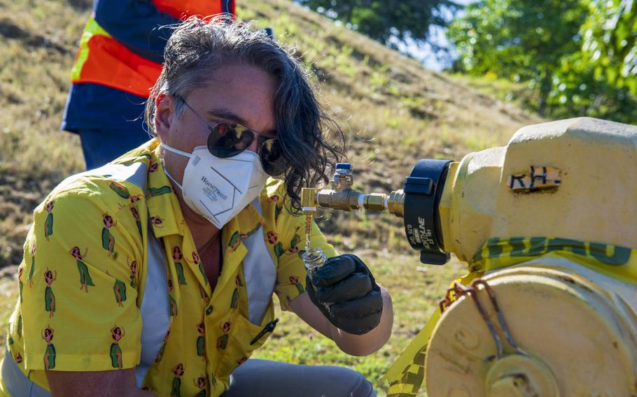 A Navy contractor collects a water sample at Red Hill Housing in Honolulu, March 11, 2022, as part of a long-term monitoring plan for drinking water contaminated by jet fuel.