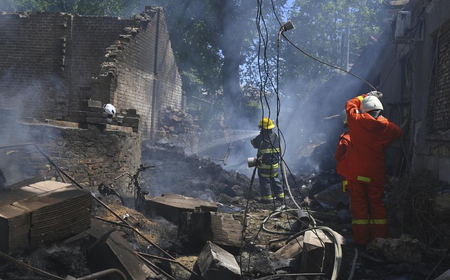 Emergency workers spray hoses on a smoldering ruin of a building.