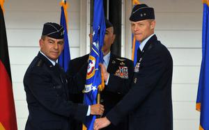 U.S. Air Forces Europe-Air Forces Africa commander Gen. Jeffrey Harrigian passes the 3rd Air Force guidon to the unit’s new commander Maj. Gen. Derek France, at an assumption-of-command ceremony at Ramstein Air Base, Germany, June 22, 2022. At center is Command Chief Master Sergeant Heriberto Diaz.