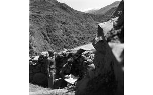 Guards look out over a sentry position in a hilly area.