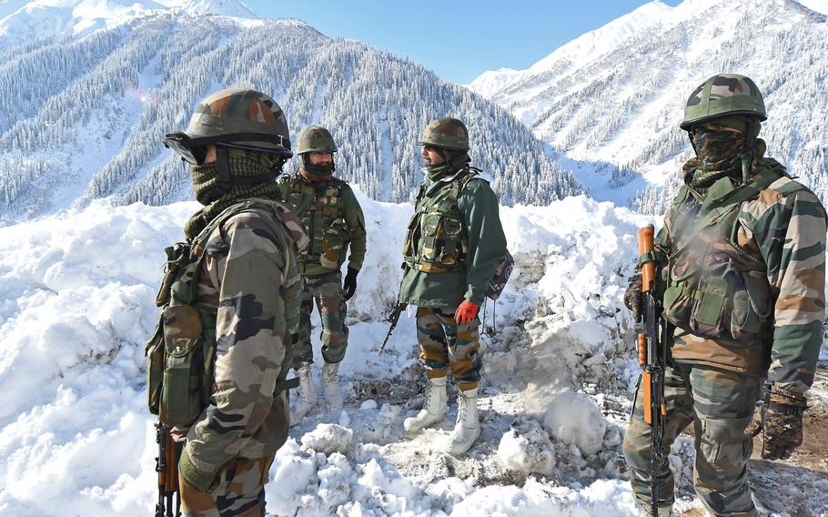 Indian army soldiers stand on a snow-covered road near Zojila mountain pass that connects Srinagar to the union territory of Ladakh, bordering China on Feb. 28, 2021. 