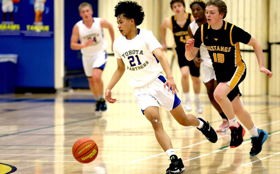 Yokota's Earl Maverick Larino dribbles upcourt past American School In Japan's Thomas Ferrette during Tuesday's Kanto Plain boys basketball game. The Panthers won 58-26.