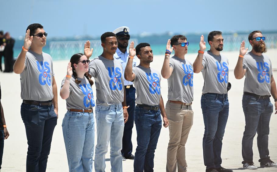 Civilians raise their right hand during a swearing-in ceremony