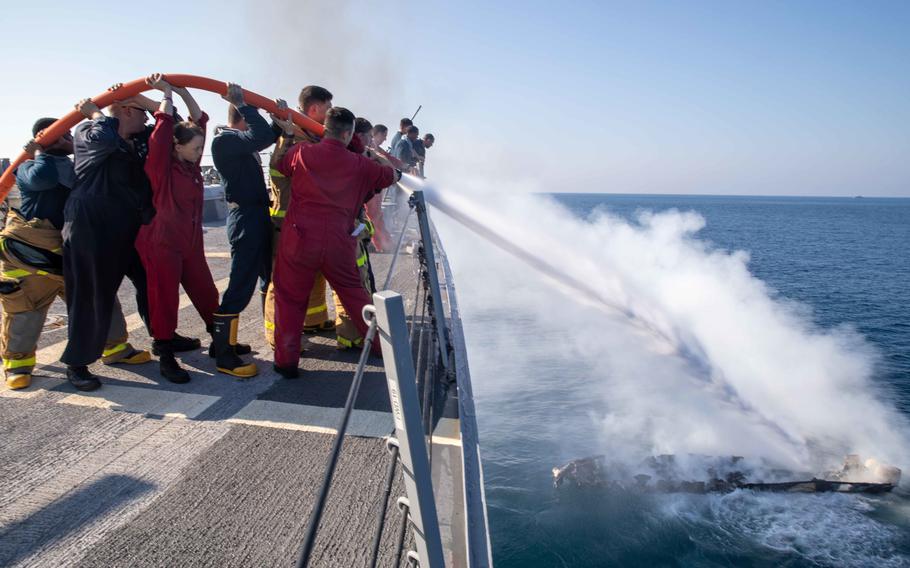 U.S. Navy sailors extinguish flames coming from a motorboat in the Gulf of Aden on Oct. 26, 2022. Crews from two Navy ships rescued three Yemenis from the burning boat.