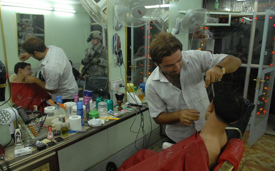 Sgt. Matthew Castine, 23, of Plattsburg, N.Y., watches as a barber tends to a customer in Gazaliyah, a once-prosperous, once-violent district in western Baghdad. During a night patrol through a market, the smell of kebabs wafted over the streets and several soldiers, wearing night vision goggles, stopped for a quick ice cream.