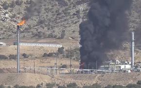 Black smoke rises from an oil field.