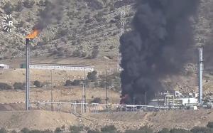 Black smoke rises from an oil field.