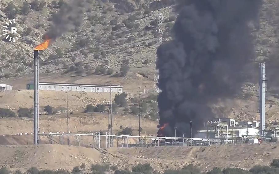Black smoke rises from an oil field.