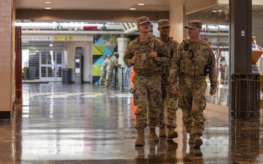 Three soldiers walk down a corridor.