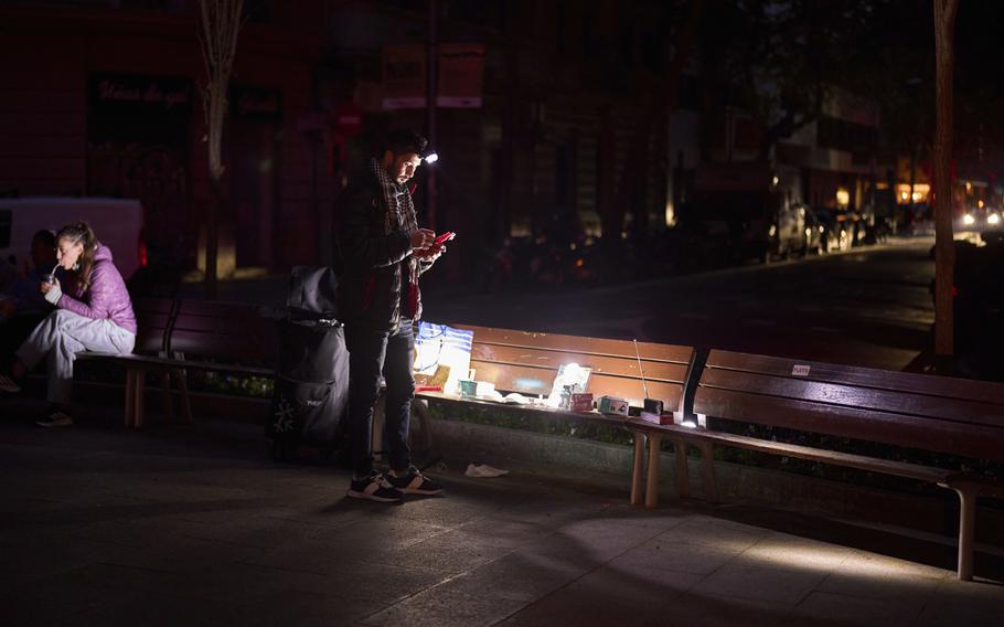 A man sells battery-powered radios and torches on a dark Barcelona street during a blackout.