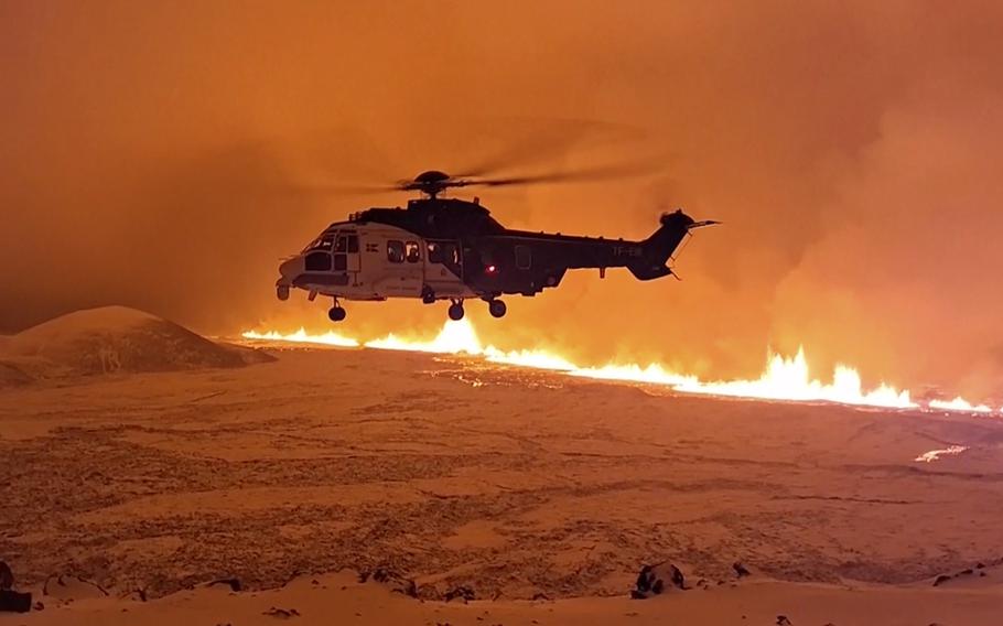 An Icelandic Coast Guard helicopter flies near magma running on a hill near Grindavik on Iceland's Reykjanes Peninsula following a volcanic eruption on Dec. 18.