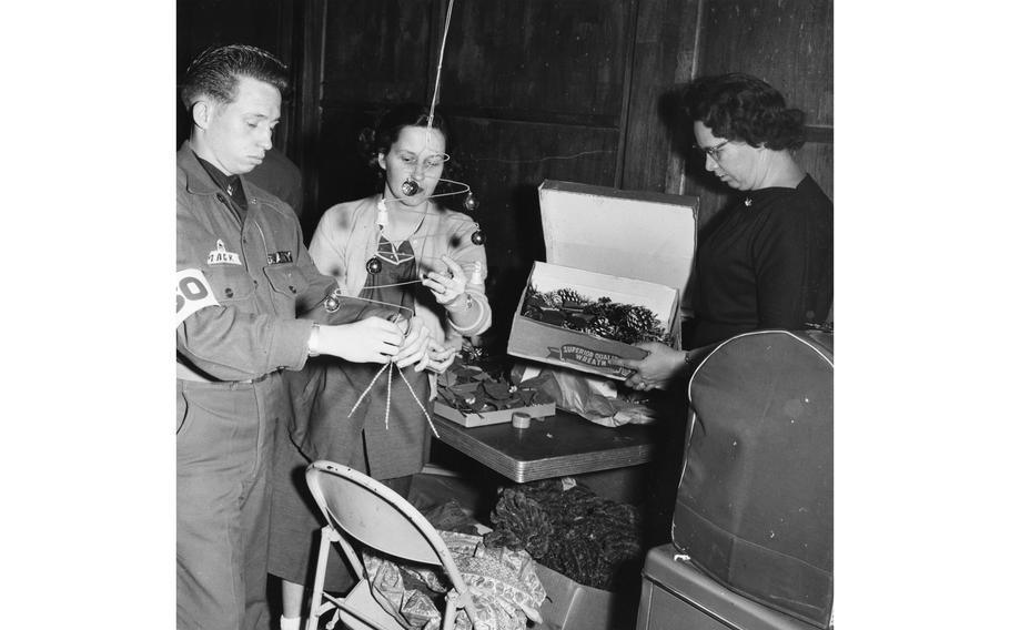 Getting into the mood for the Christmas season, this USO group puts special touches to holiday decorations at the Seoul USO, Dec. 23, 1995. They are, from left, Pfc. Robert Mack, Headquarters Company, 1st Battle Group, 17th Infantry, 7th Division; Edna Rae Sedwell, Methodist Mission, and George Engel, wife of the USO director.