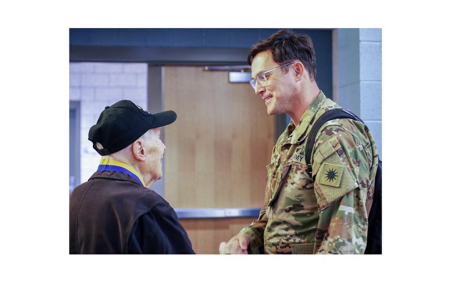 Chief Warrant Officer 4 Ryan Schwend, CH-47 pilot, 1st Battalion, 168th General Support Aviation shakes hands with Capt. Dick Nelms, World War II pilot during a presentation of the Knight of the Honorable Order of Saint Michael award at the Washington Army National Guard Aviation Readiness Center, Joint Base Lewis-McChord, Wash., on Sunday, March, 3, 2024.