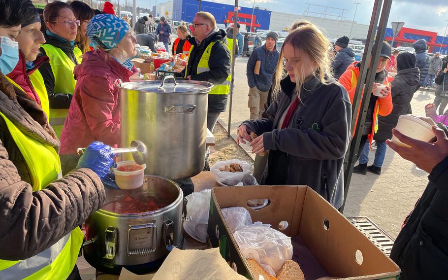 Volunteers ladle out steaming hot borscht at a makeshift welcome center for refugees in a supermarket parking lot in Przemyśl. 
