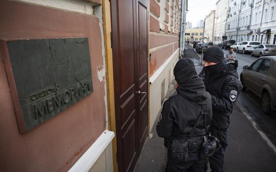 Two Russian police officers stand in front the door of the Memorial office in Moscow, Russia, Tuesday, March 21, 2023. The Russian authorities on Tuesday raided homes and offices of multiple human rights advocates and historians with the prominent rights group Memorial that won the Nobel Peace Prize last year. (AP Photo)