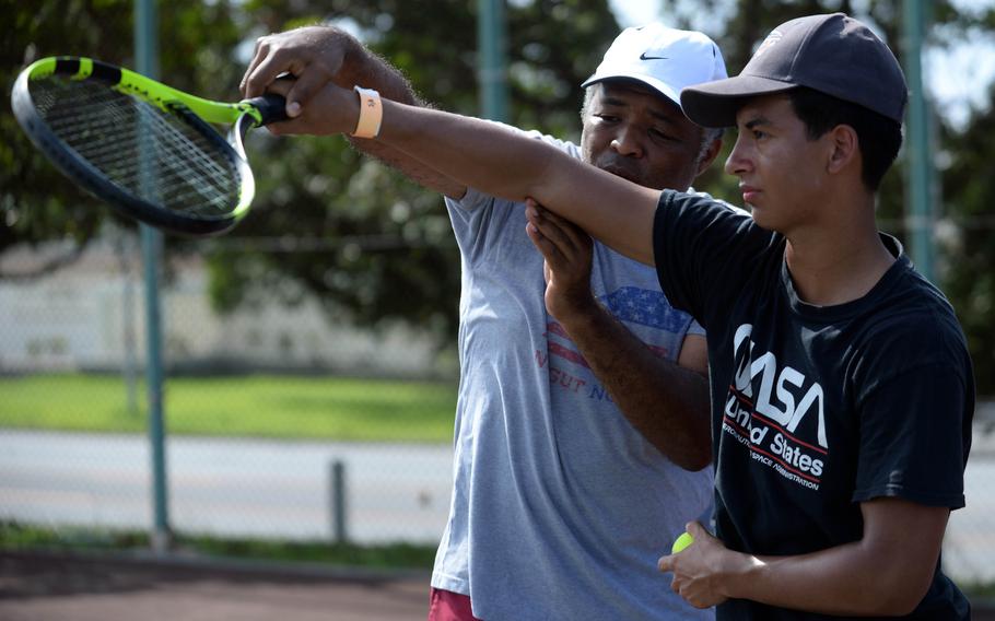 Kadena tennis coach Shawn Ryan gives some serving tips to Panthers freshman Gabriel Fino.