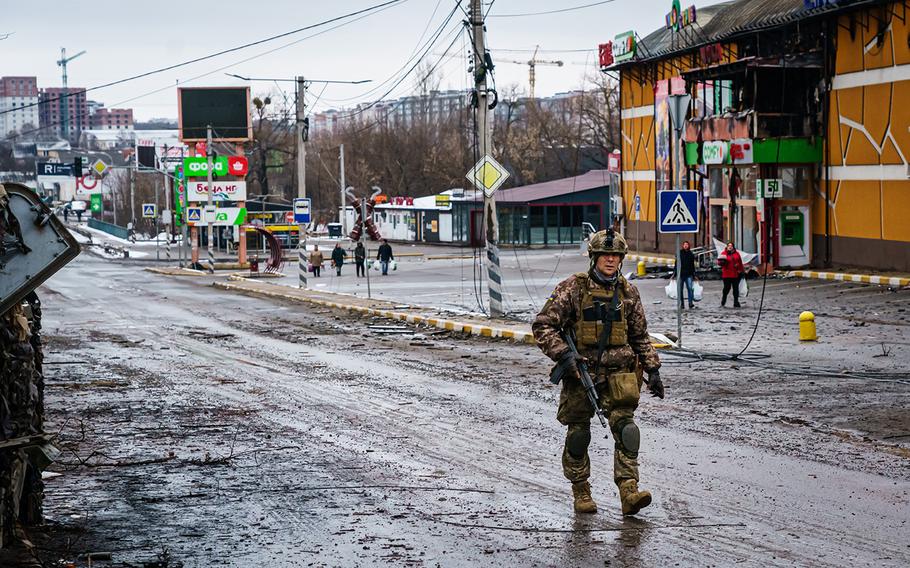 A Ukrainian soldier walks past a building that was destroyed in the midst of battle with the Russians, on the outskirts of Irpin, Ukraine, Tuesday, March 1, 2022.