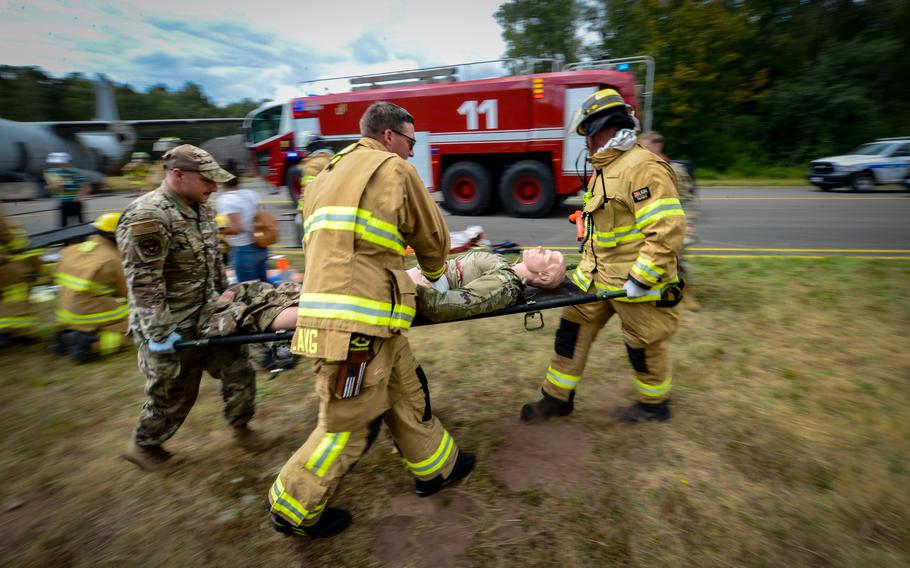 Firefighters and security forces members transport a victim during a simulated aircraft crash scenario exercise at Ramstein Air Base, Germany, July 26, 2022.