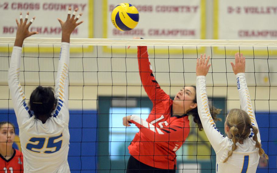 E.J. King's Mackinzi Dudley spikes between Yokota's Trinity Stegall and Emma Hardy during Friday's DODEA-Japan volleyball match. The Cobras won in straight sets.