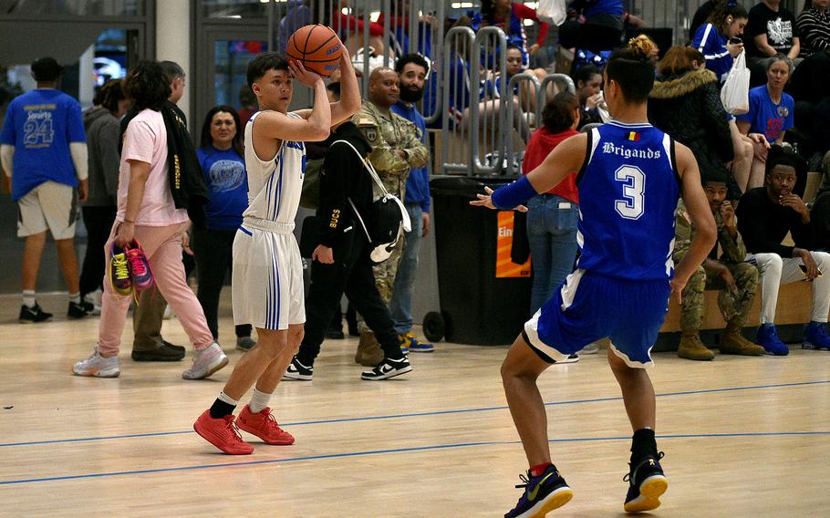 Hohenfels junior Theo Reyes shoots a 3-pointer as Brussels’ Asher Jorgensen reaches out to defend during pool-play action of the DODEA European basketball championships on Feb. 14, 2024, at the Wiesbaden Sports and Fitness Center on Clay Kaserne in Wiesbaden, Germany.