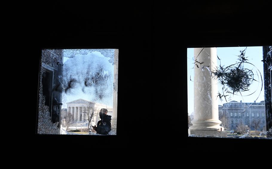 A police officer is visible through a broken window of the U.S. Capitol on Jan. 7, 2021, the day after a pro-Trump mob broke into the building. MUST CREDIT: Washington Post photo by Matt McClain
