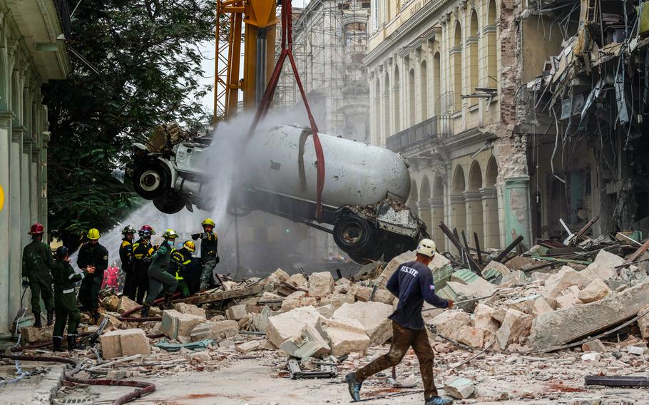 Firefighters spray a tanker truck with water in order to cool it down as they remove it from the site of a deadly explosion that destroyed the five-star Hotel Saratoga, in Havana, Cuba, Friday, May 6, 2022.