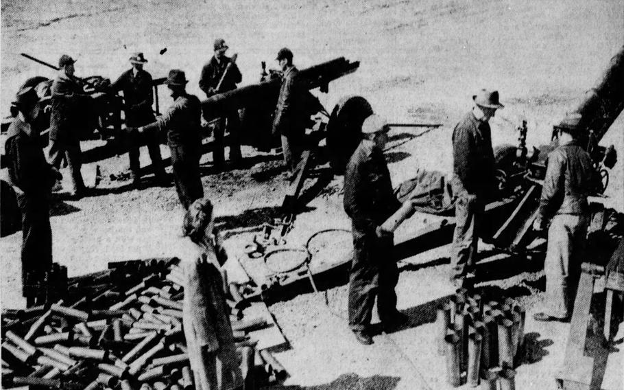 A gun crew tests ammunition on the Jefferson Proving Ground in March 1943. A woman blows the whistle as a firing signal while a group of reporters watch.