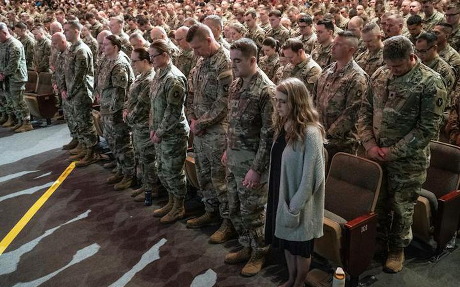 First Lt. Caleb Hjelle and his wife Regan Hjelle, right, bow their heads during the benediction of the deployment ceremony for 550 members of the Minnesota National Guard’s 34th Infantry Division Red Bulls on Thursday, Feb. 1, 2024, in Eden Prairie, Minn.