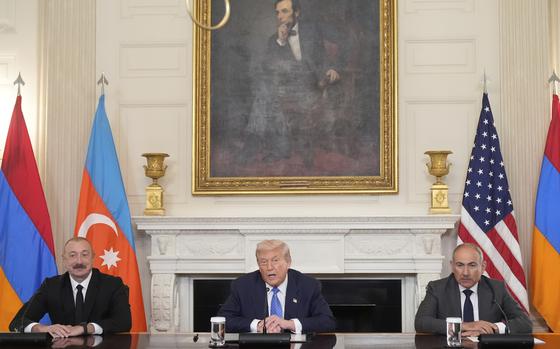 The leaders of Azerbaijan, the U.S. and Armenia seated at a long conference table, all with their arms folded before them.