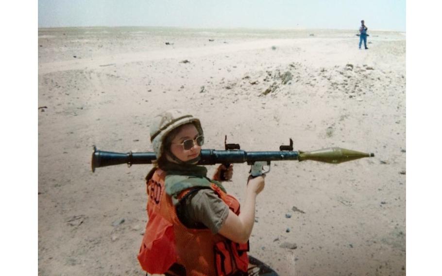 Belle Crause holding an explosive weapon in the desert