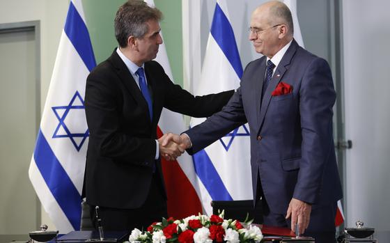 Poland's Minister of Foreign Affairs Zbigniew Rau, right, and his Israeli counterpart Eli Cohen, left, shake hands after signing an agreement allowing the resumption of Israeli youth trips to Poland in Warsaw, Poland, Wednesday, March 22, 2023. (AP Photo/Michal Dyjuk)