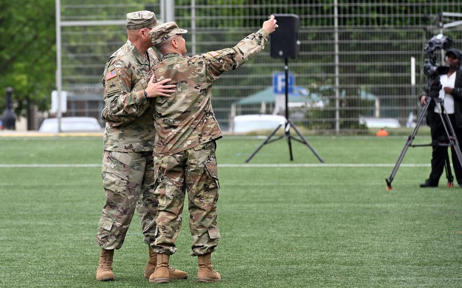 Two men in Army uniforms take a selfie, each with an arm on the other’s back.