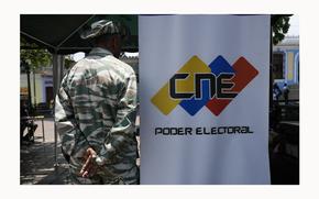 FILE - A Bolivarian Militia member stands on guard next to a banner of the National Electoral Council (CNE) where people can register to vote in the presidential election in Caracas, Venezuela, April 16, 2024. On May 28, 2024, Venezuela’s electoral authorities revoked an invitation for a European Union mission to observe the country's July 28 presidential election. (AP Photo/Ariana Cubillos, File)