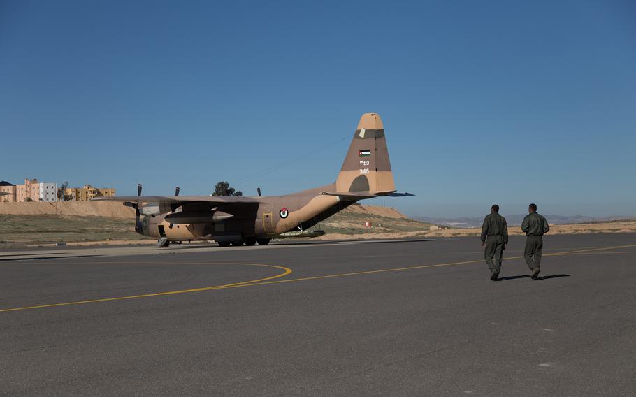Two members of Jordan's air force walk toward a C-130 at King Abdullah II Air Base that is set to deliver aid to Gaza. 