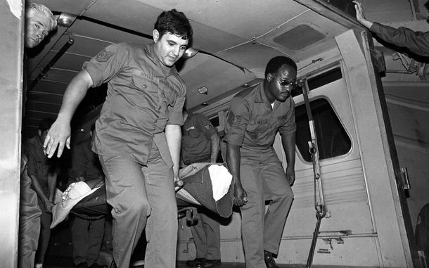 In this black and white photo, men carry a burn victim out of an ambulance.