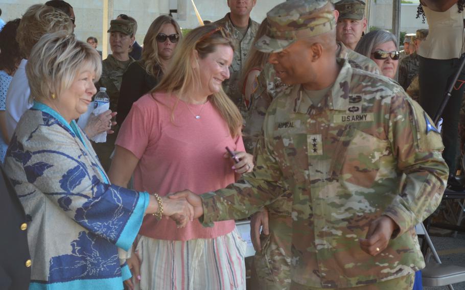 Army officer shakes hands with a woman in a crowd of people.
