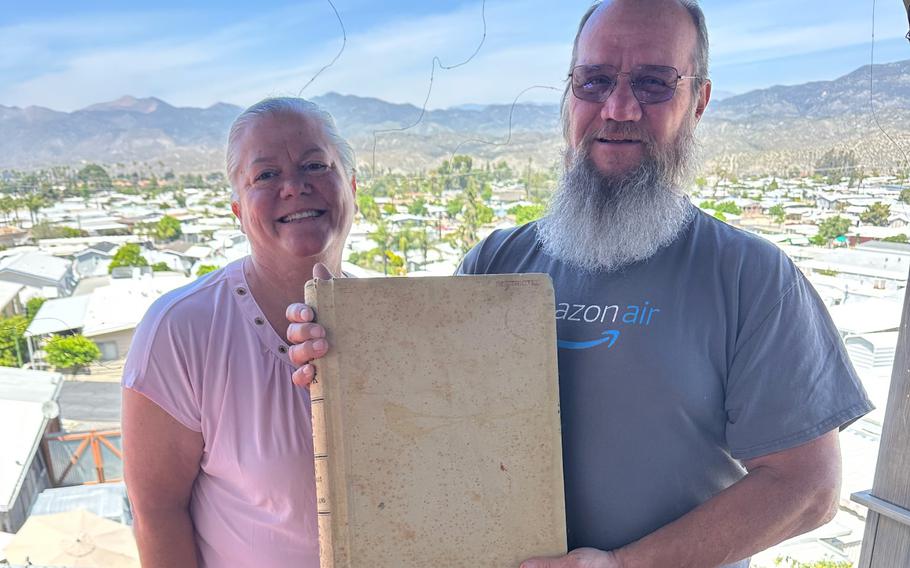 Bonds holds the log book, and Sharrit stands next to him.