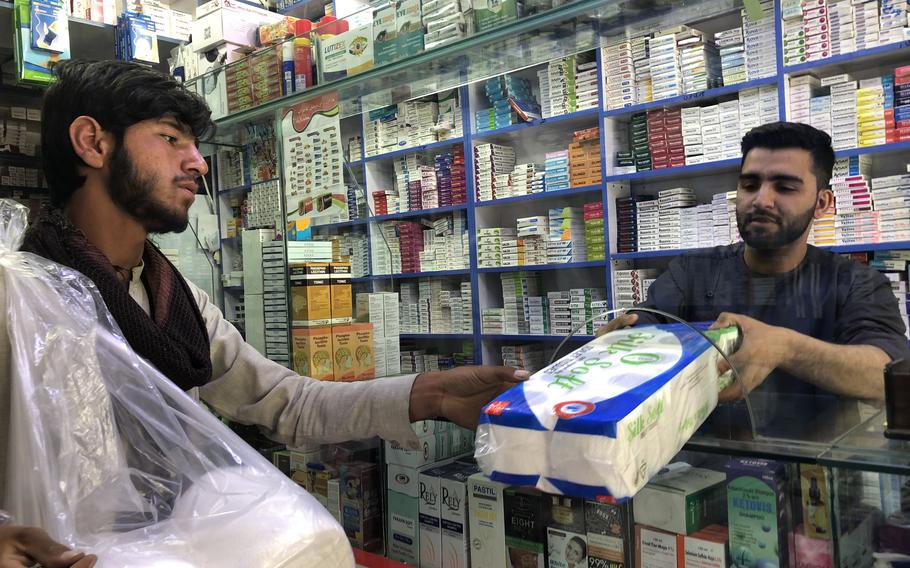 Karzai Balochkhel, 16, sells toilet paper to pharmacist Murtaza Khaleqe in Kabul on April 16, 2022..
