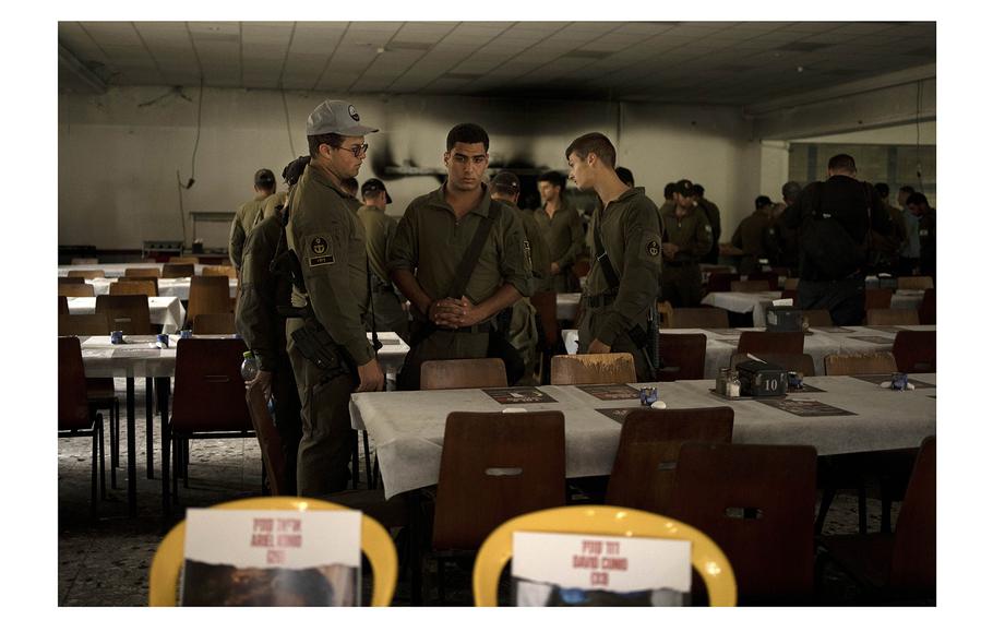 Israeli soldiers look at chairs for hostages held in Gaza at a Passover Seder table on Thursday, April 11, 2024, at the communal dining hall at Kibbutz Nir Oz in southern Israel, where a quarter of all residents were killed or captured by Hamas on Oct. 7, 2023. 