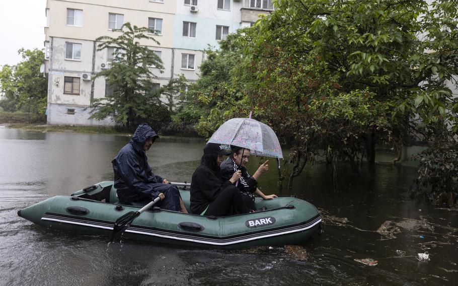 Katia Lysenko, 40, points as she travels in a dinghy from her flooded apartment after feeding her cats in Kherson, Ukraine.