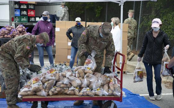 North Carolina Army National Guard Soldiers assigned to 5th Battalion, 113th Field Artillery Regiment, and other volunteers stack bags of potatoes that are being distributed to veterans and military families in Hillsborough, North Carolina on May 13, 2020. The military-themed food distribution was coordinated by Orange County Social Services. More than 900 NCNG Soldiers and Airmen have been activated in response to COVID-19 relief efforts to help support NC Emergency Management, N.C. Department of Health and Human Services, and their local communities. (U.S. Army photo by Staff Sgt. Mary Junell)