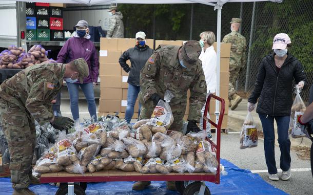 North Carolina Army National Guard Soldiers assigned to 5th Battalion, 113th Field Artillery Regiment, and other volunteers stack bags of potatoes that are being distributed to veterans and military families in Hillsborough, North Carolina on May 13, 2020. The military-themed food distribution was coordinated by Orange County Social Services. More than 900 NCNG Soldiers and Airmen have been activated in response to COVID-19 relief efforts to help support NC Emergency Management, N.C. Department of Health and Human Services, and their local communities. (U.S. Army photo by Staff Sgt. Mary Junell)
