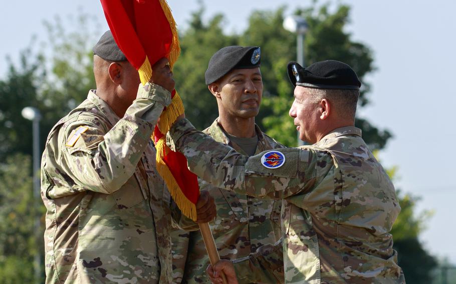 The outgoing head of the 56th Artillery Command, Maj. Gen. Stephen Maranian, passes the unit colors to Gen. Darryl Williams, U.S. Army Europe and Africa commander, as Brig. Gen. Andrew Gainey, the new commander of the 56th, waits to receive them July 11, 2023, at Clay Kaserne in Wiesbaden, Germany.