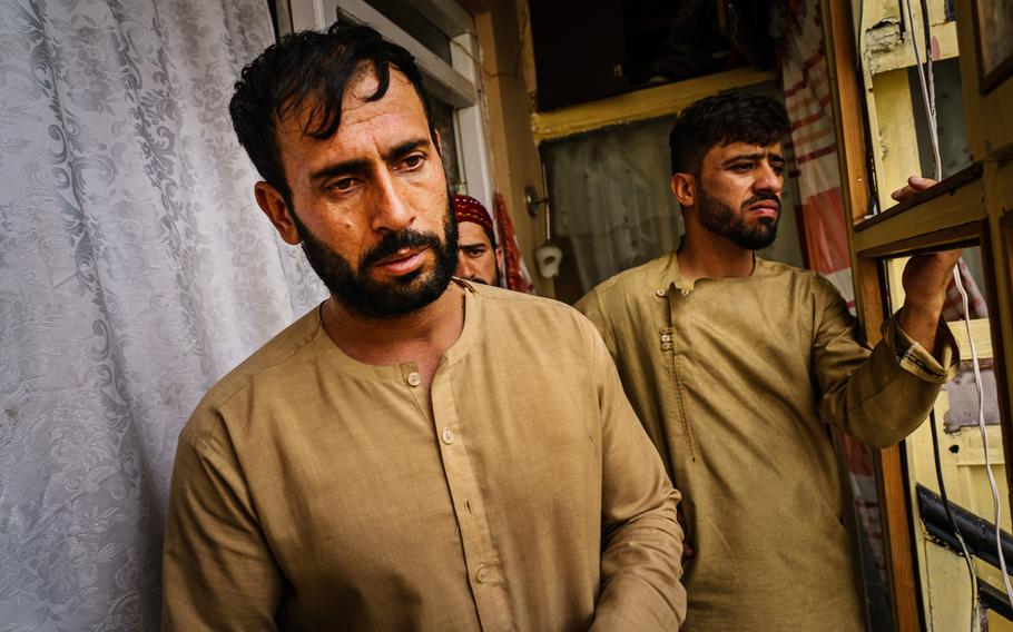 Emal Ahmadi, left, looks off into the distance as relatives around him try to provide support after a U.S. drone strike killed members of his family in Kabul, Afghanistan.