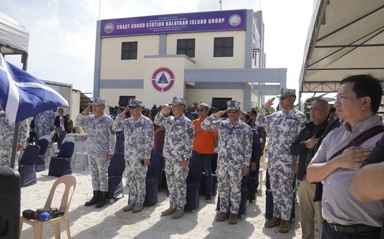 Coast guard officers salute during ceremonies for the inauguration of their new building at the Philippine-occupied Thitu island, locally called Pag-asa island, on Friday, Dec. 1, 2023, at the disputed South China Sea. The Philippine coast guard inaugurated a new monitoring base Friday on a remote island occupied by Filipino forces in the disputed South China Sea as Manila ramps up efforts to counter China's increasingly aggressive actions in the strategic waterway. (AP Photo/Aaron Favila)