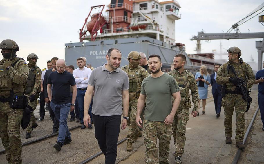 Ukraine President Volodymyr Zelenskyy, center, surrounded by ambassadors of different countries and UN officials, visits a port in Chornomork during loading of grain on a Turkish ship, background, close to Odesa, Ukraine, Friday, July 29, 2022. 