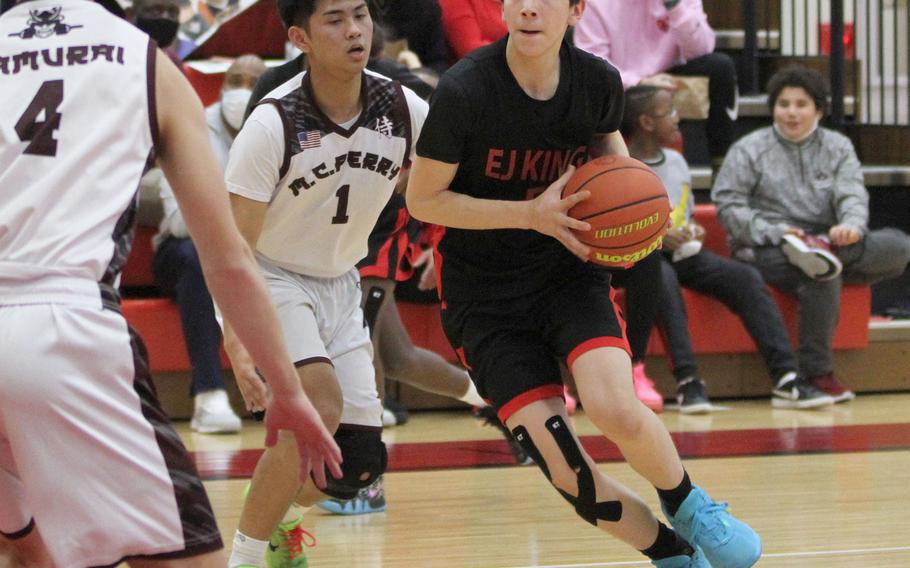 E.J. King's Cameron Reinhart dribbles against Matthew C. Perry's Joshua Blanquisco during Friday's DODEA-Japan boys basketball game. The Samnurai won 50-31.