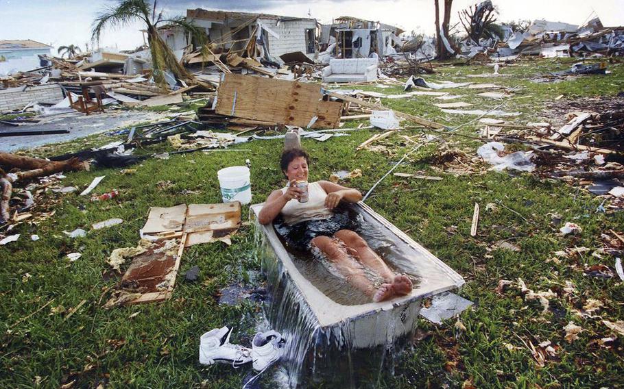 Marjorie Conklin cools off in a tub of water filled by a hose, surrounded by what’s left of her home and the homes of others at the Goldcoaster Mobile Home and RV park in Florida City in the wake of Hurricane Andrew’s devastation.