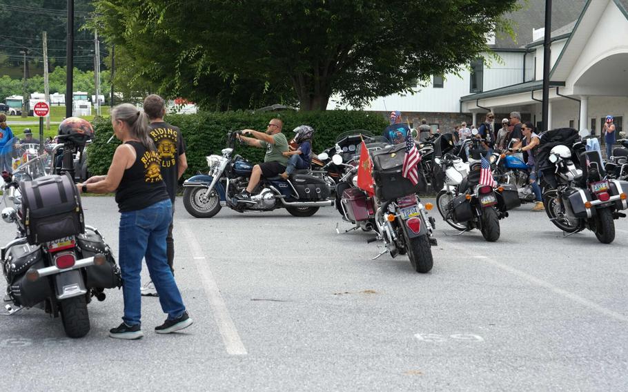 People with motorcycles gathered in a parking lot.